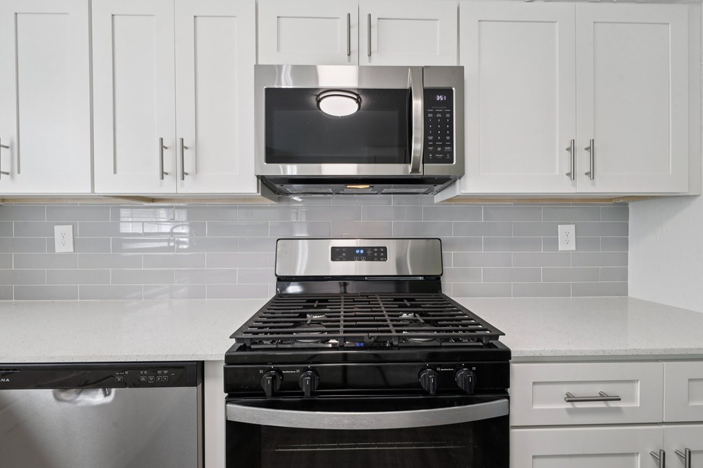 A modern kitchen with a stove top oven and microwave above it.