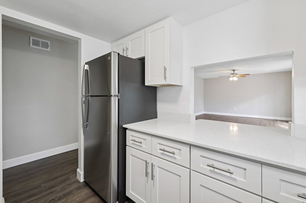 A kitchen with a refrigerator, cabinets, and a countertop.
