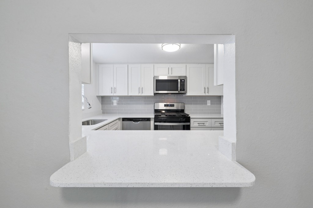 A white kitchen with a microwave on the counter.