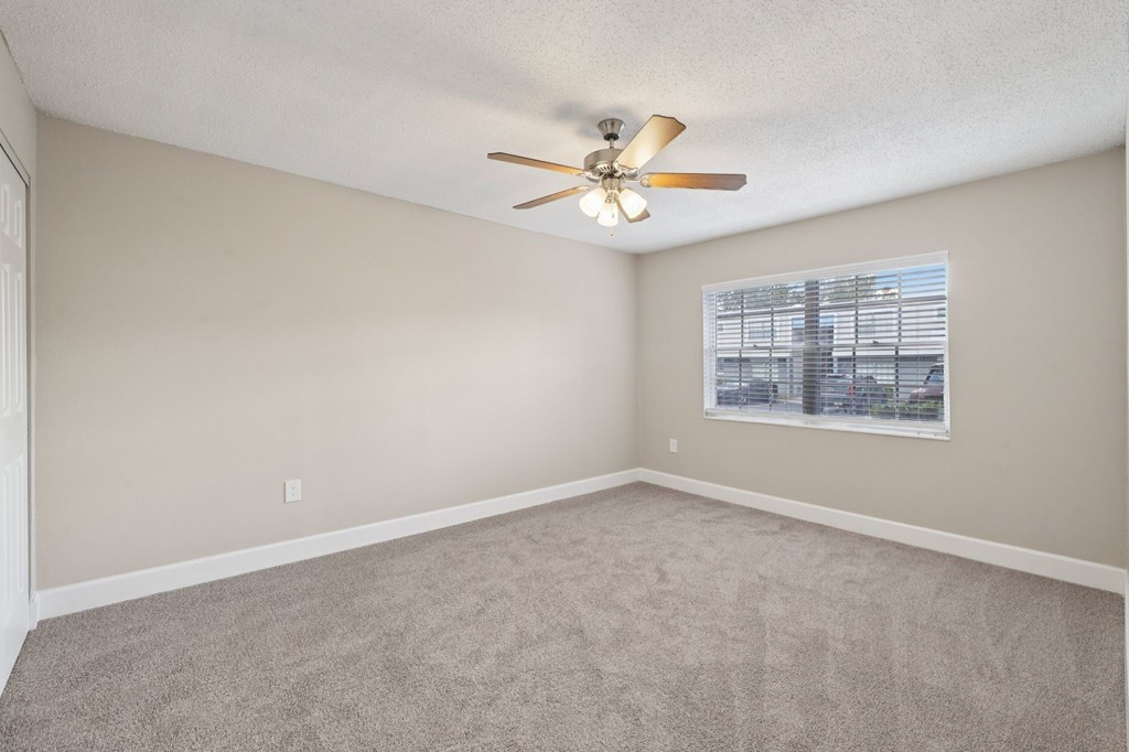 Empty room with a ceiling fan and a window.