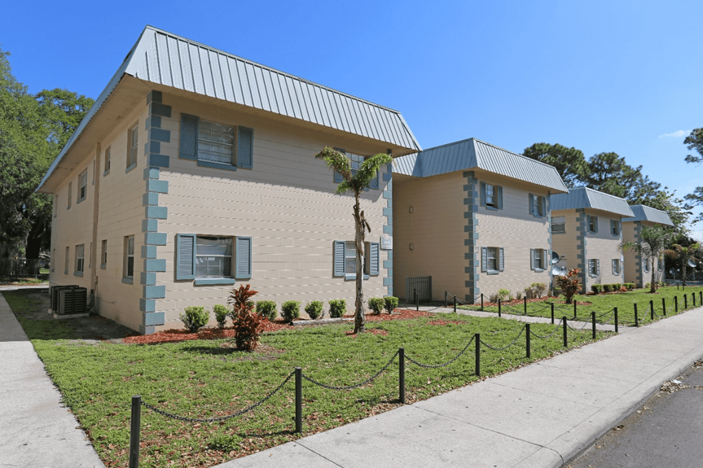 A row of houses with a sidewalk and a fence in front.