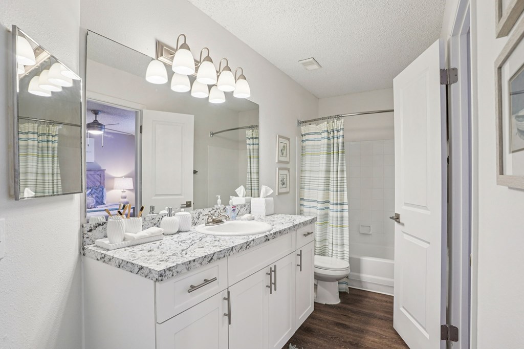 A bathroom with a marble countertop and white cabinets.