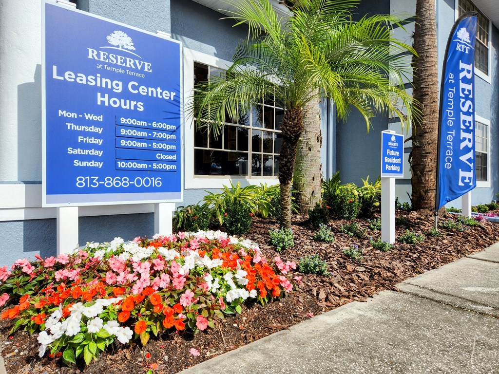 a building with a blue sign and flowers in front of it at Reserve at Temple Terrace, Florida, 33637