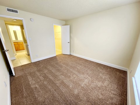 an empty living room with carpeting and a door to a bathroom at Sunscape Apartment Homes, Florida, 33613