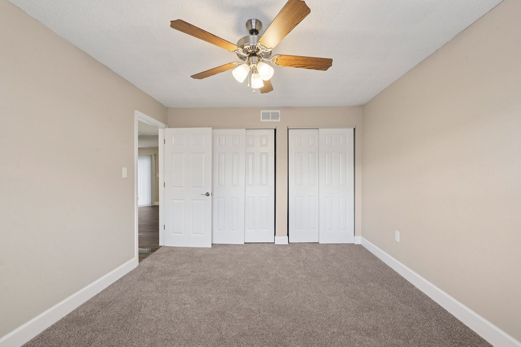 A room with a ceiling fan and carpeted floor.