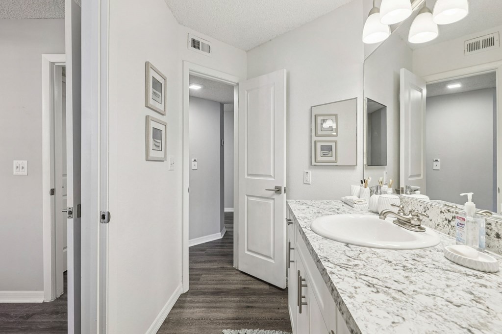 A bathroom with a marble countertop and a white sink.