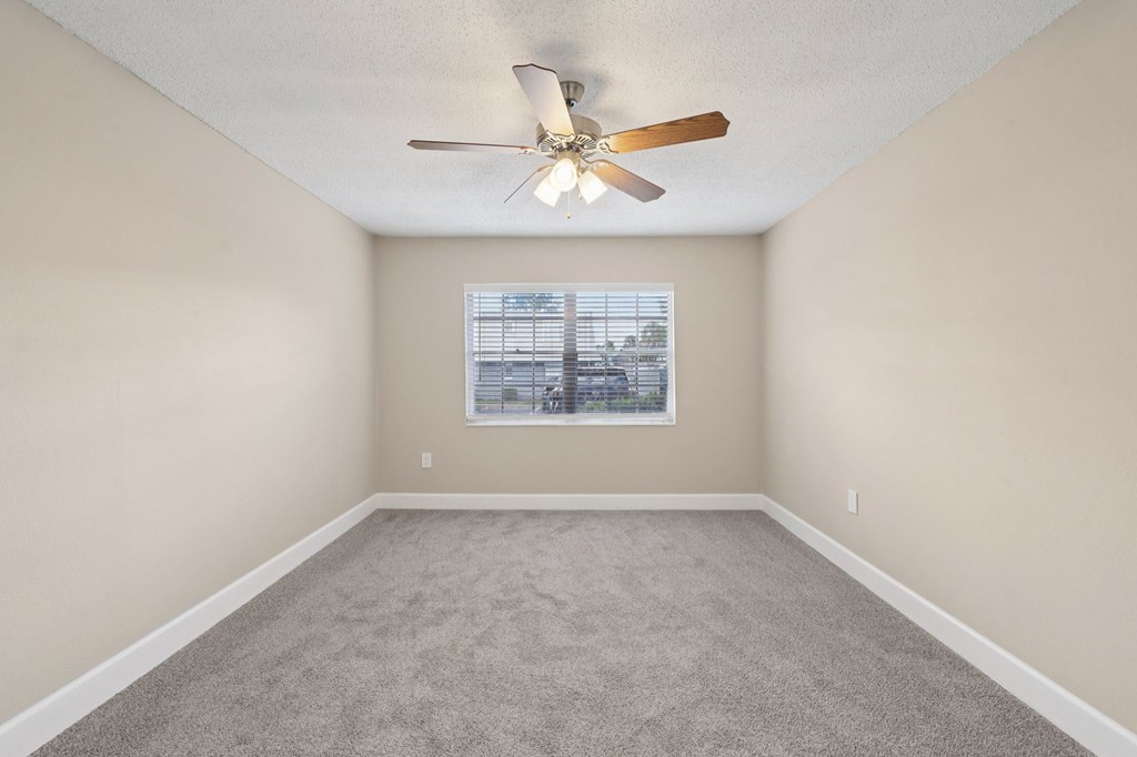 A room with a ceiling fan and a window with blinds.