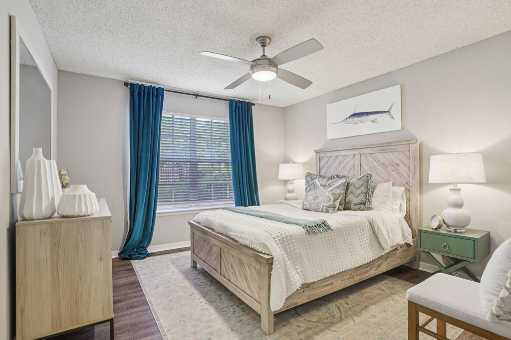 A bedroom with a bed, nightstand, and a ceiling fan.