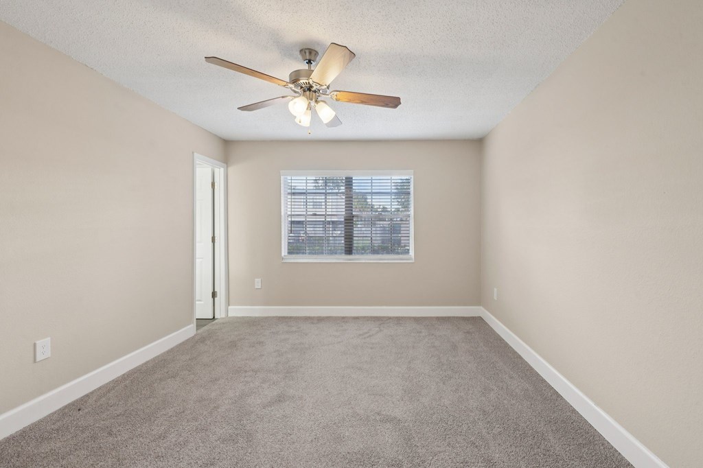 A room with a ceiling fan and a window with blinds.