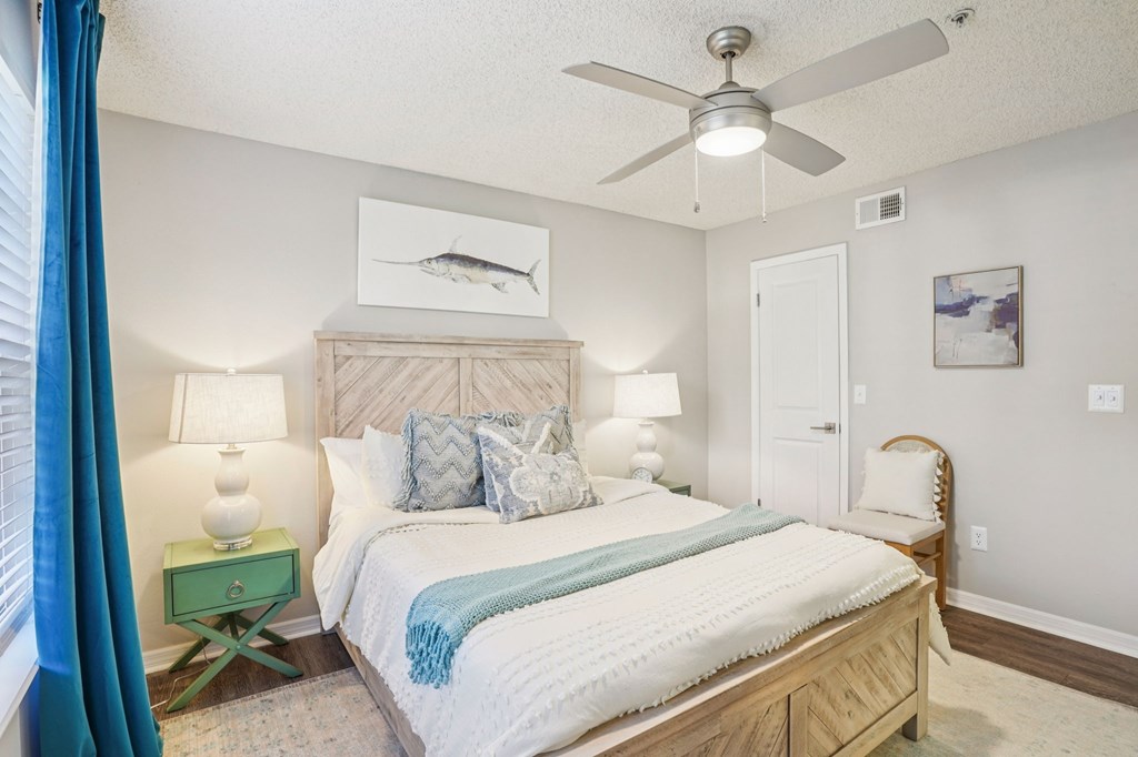 A bedroom with a bed, nightstand, and a ceiling fan.