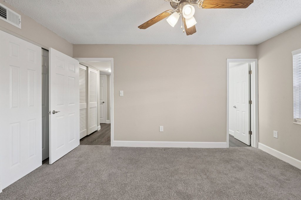A room with a ceiling fan and carpeted floor.