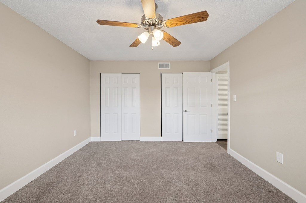 A room with a ceiling fan and carpeted floor.