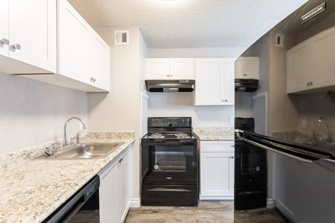 A kitchen with a black oven and white cabinets.