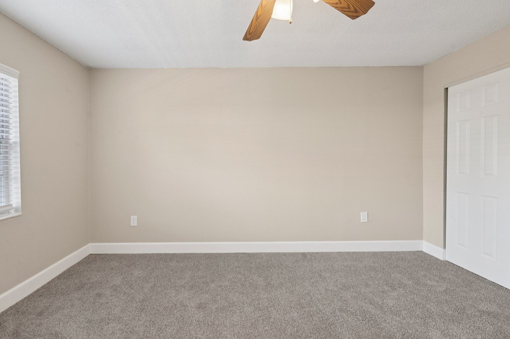 A room with a ceiling fan and a door.