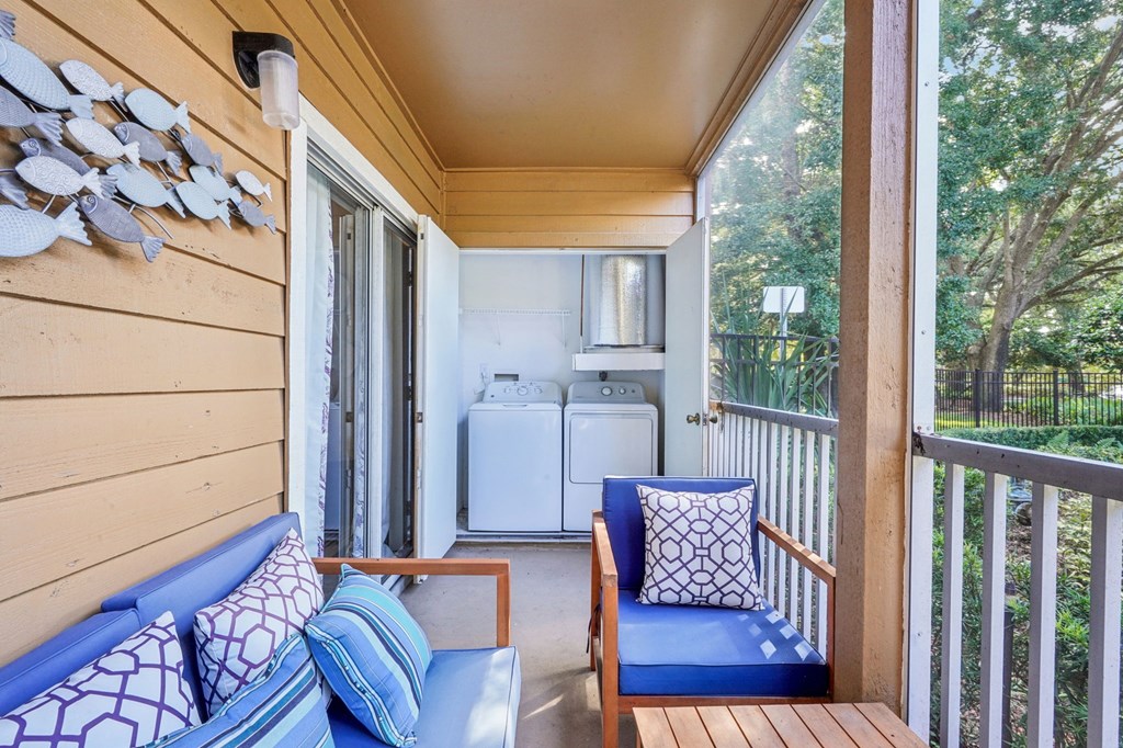 A blue couch with a white pillow is on a wooden balcony.