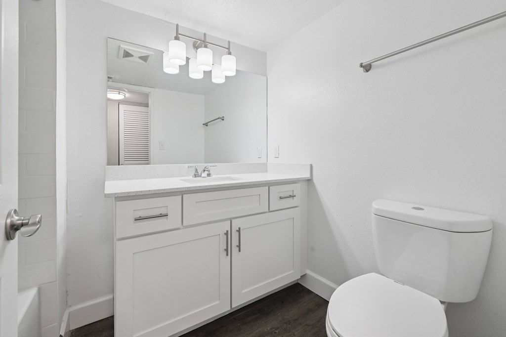 A white bathroom with a toilet, sink, and mirror.