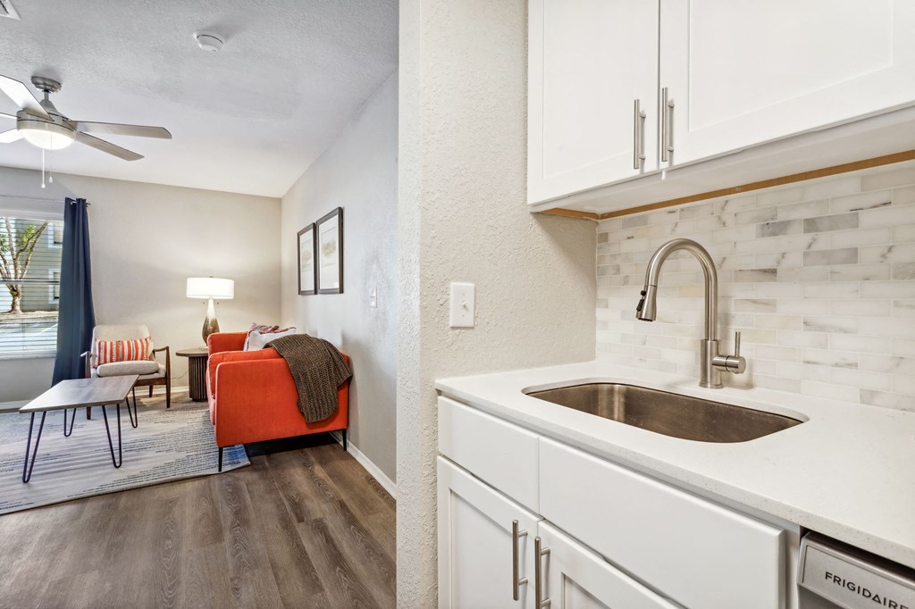 a kitchen with white cabinets and a sink and a living room at Reserve at Temple Terrace, Temple Terrace, FL