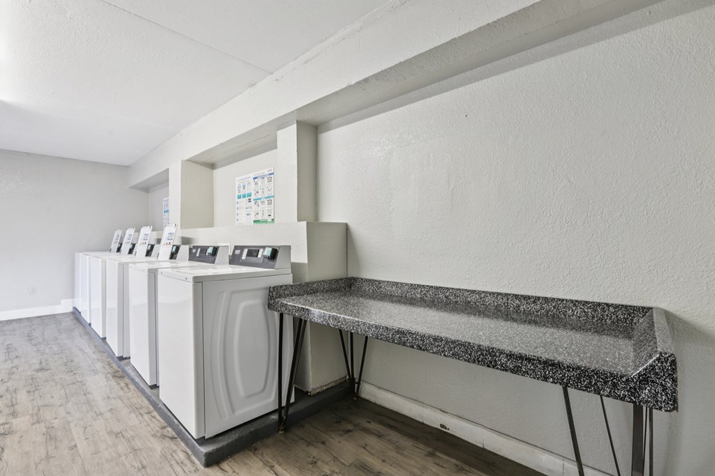 A laundry room with a washer and dryer on the left and a bench on the right.