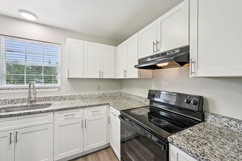 A kitchen with white cabinets and granite countertops.
