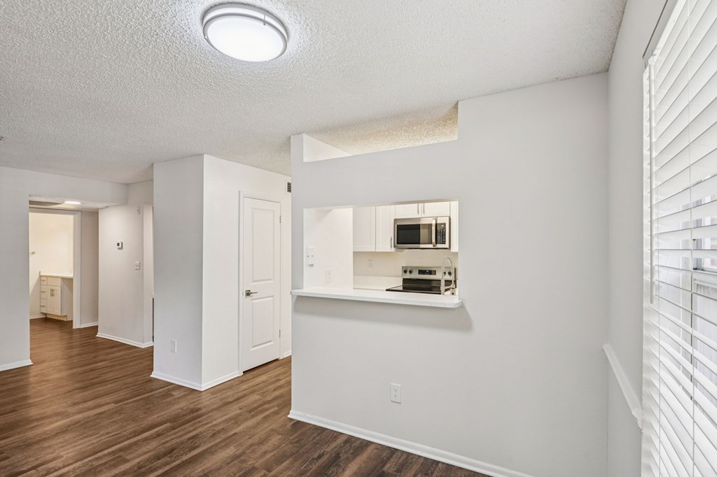 A white room with a wooden floor and a window with blinds.