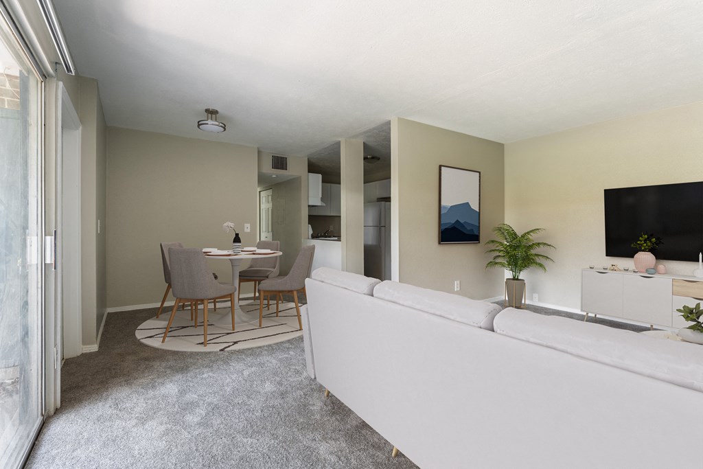 A living room with a grey sofa and a dining table with chairs.