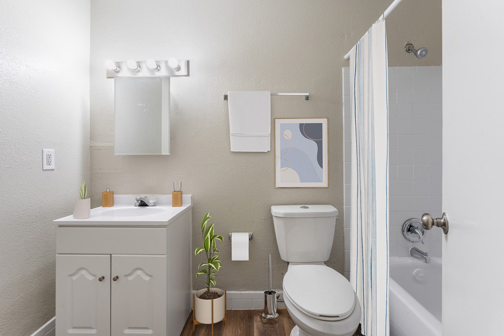A bathroom with a white toilet, sink, and a plant.