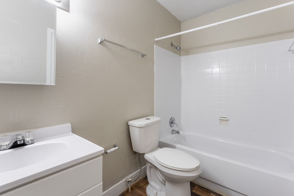 A white toilet sits next to a white sink in a small bathroom.