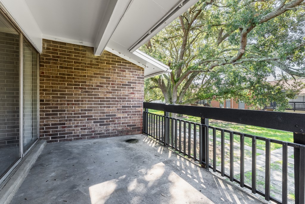A balcony with a black railing and a brick wall.