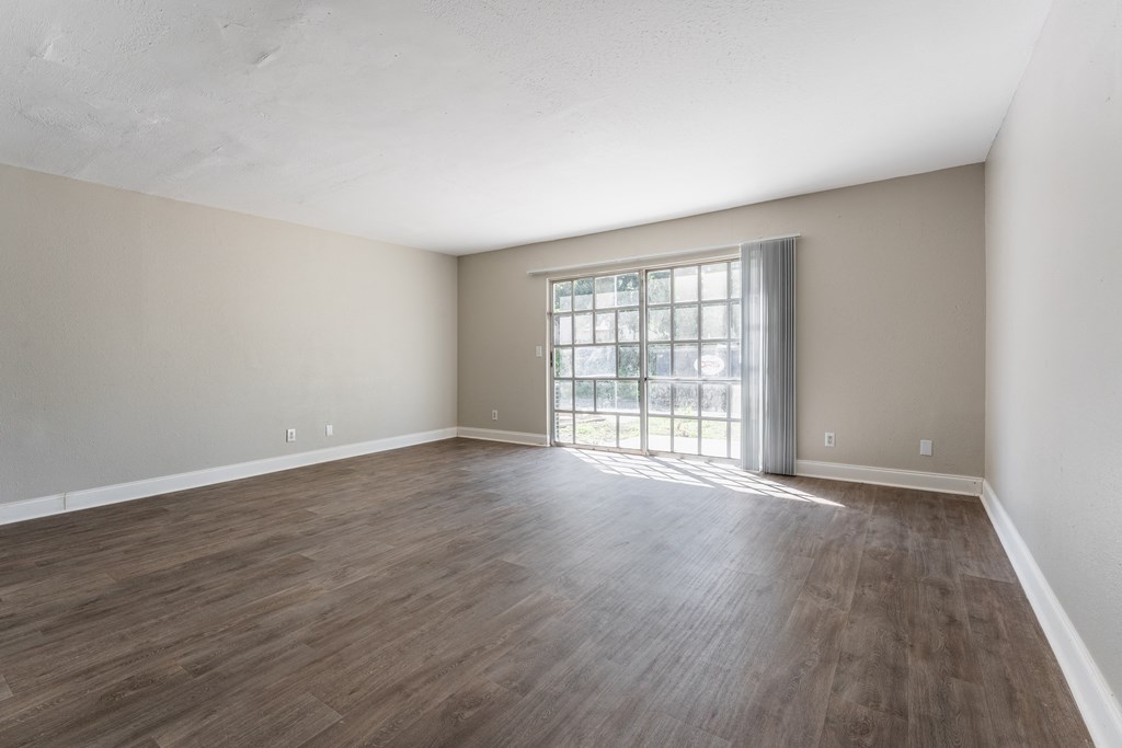 A room with wooden flooring and a large window.