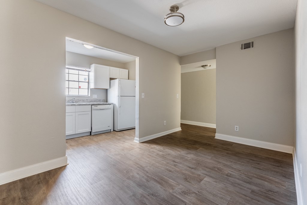 A kitchen with white appliances and a window is visible from a living room.