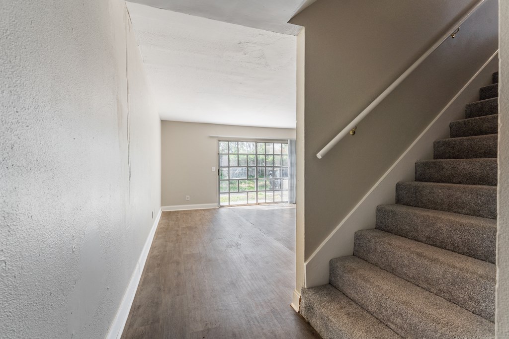 A staircase with a carpeted runner and a window with bars.