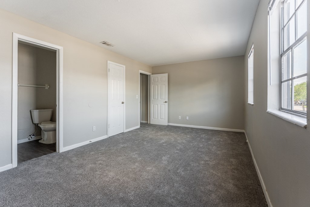 A room with a carpeted floor and a window on the right side.