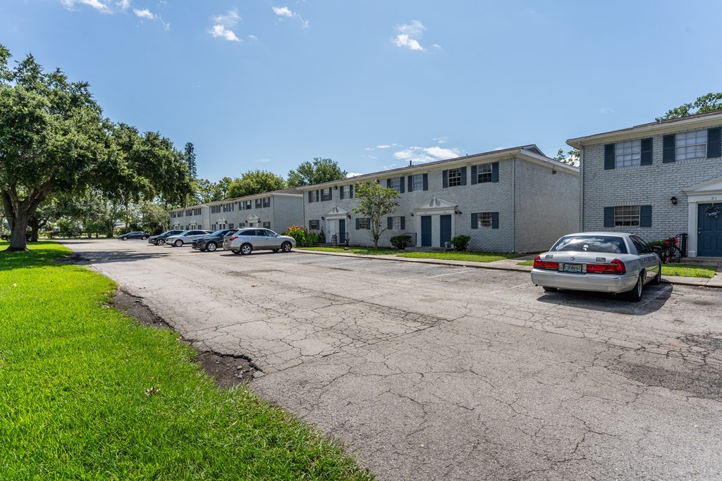 A parking lot in front of a building with a car parked in it.