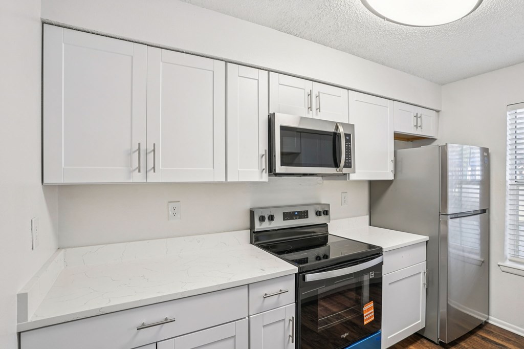 A kitchen with white cabinets and appliances.