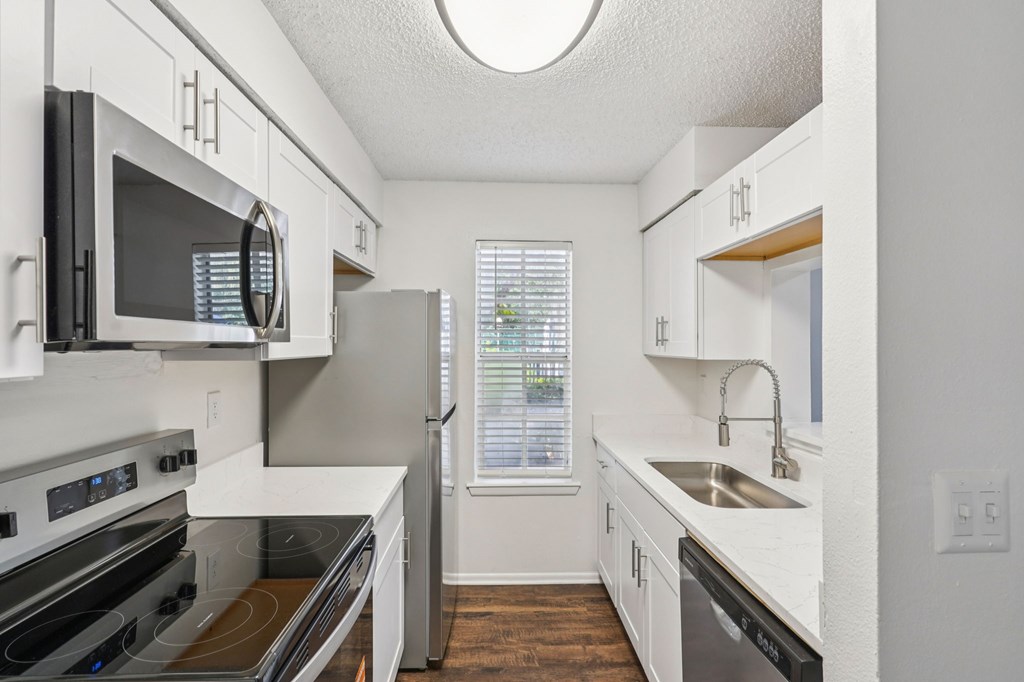 A kitchen with white cabinets and a black microwave.