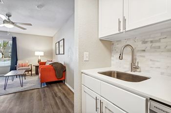 a kitchen with white cabinets and a sink and a living room with a couch at Reserve at Temple Terrace, Temple Terrace, 33637