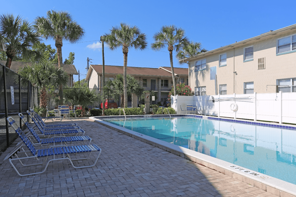 A pool surrounded by palm trees and chairs.