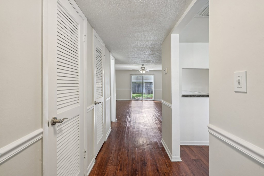 A long hallway with white walls and wood floors.