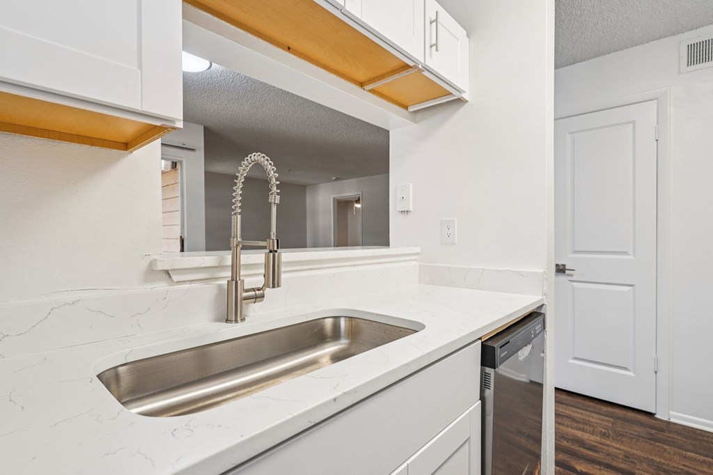 A kitchen with a white sink and a white counter top.