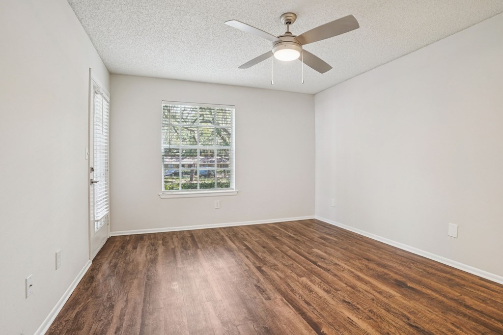 A room with a ceiling fan and a window with blinds.