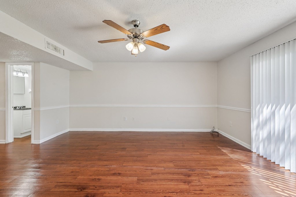A room with a ceiling fan and wooden flooring.