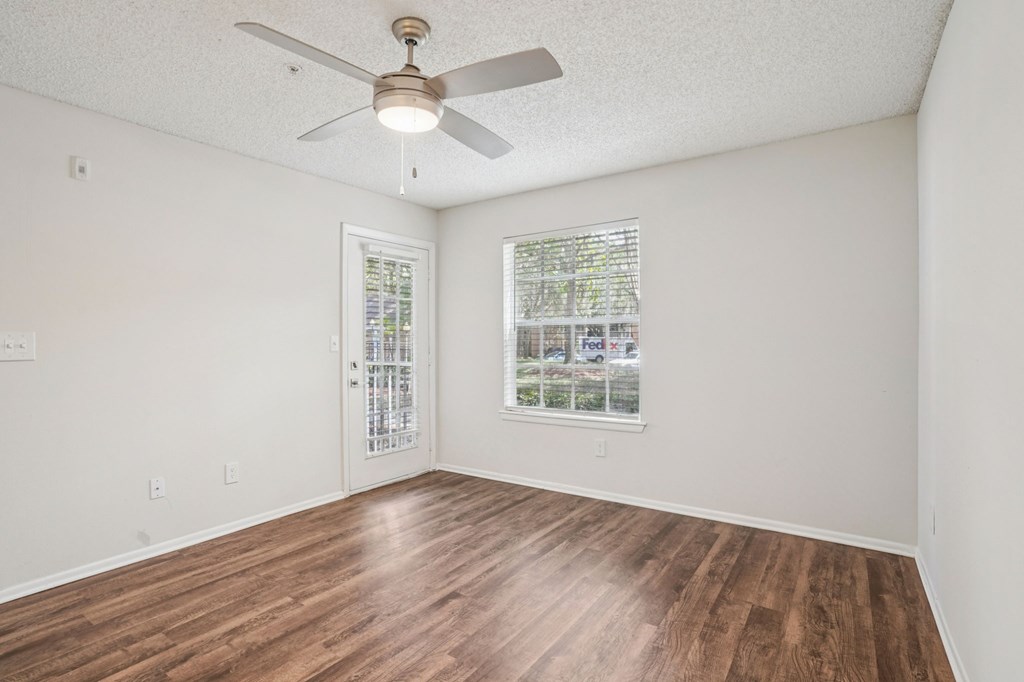 A room with a ceiling fan and wooden flooring.