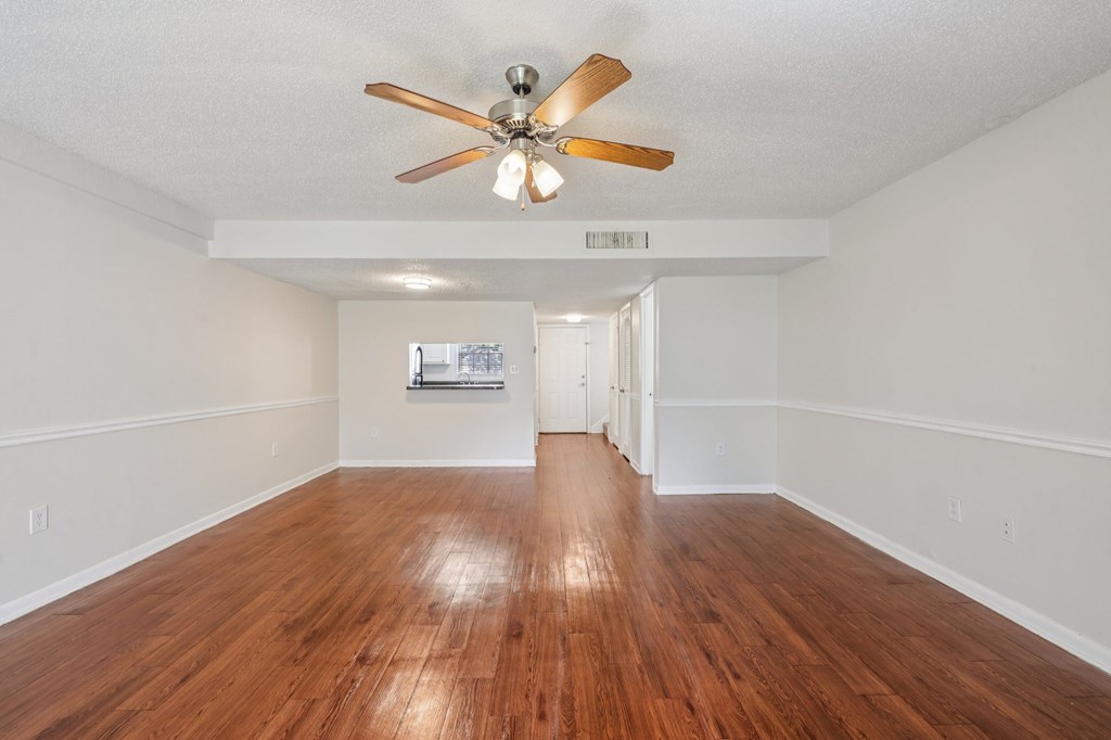A room with a ceiling fan and wooden floors.