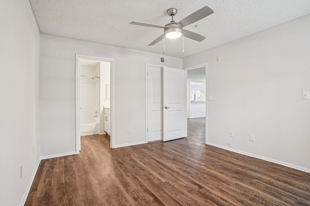 A room with a ceiling fan and wood flooring.