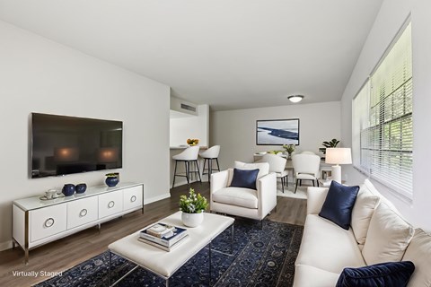 A living room with white furniture and a flat screen TV mounted on the wall.