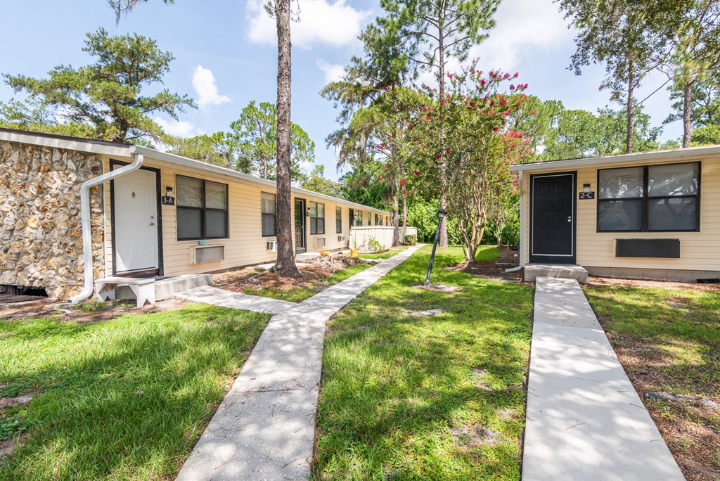 a row of yellow houses with trees and a sidewalk
