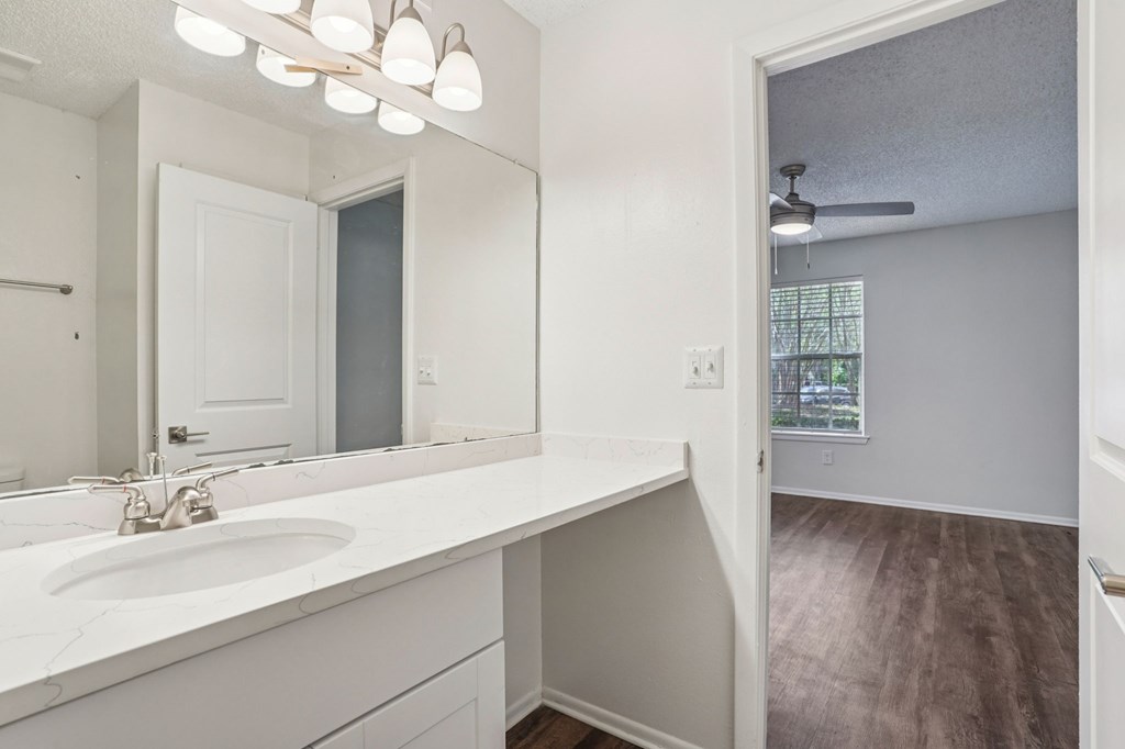 A bathroom with a white sink and mirror.