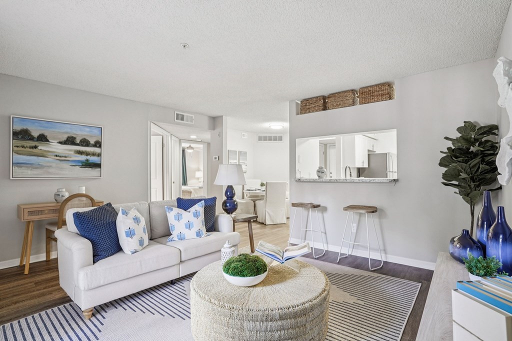 A living room with a white couch and a painting on the wall.