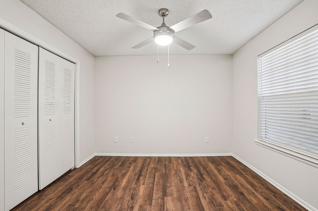 A room with a ceiling fan and wooden flooring.