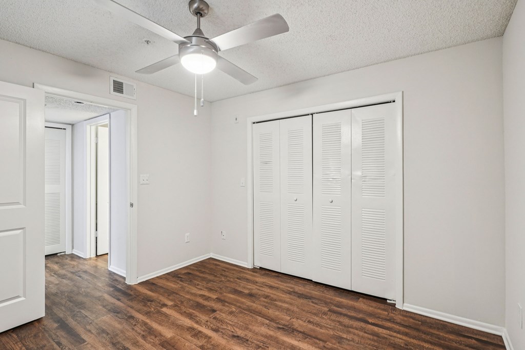 A room with a ceiling fan and wooden floors.